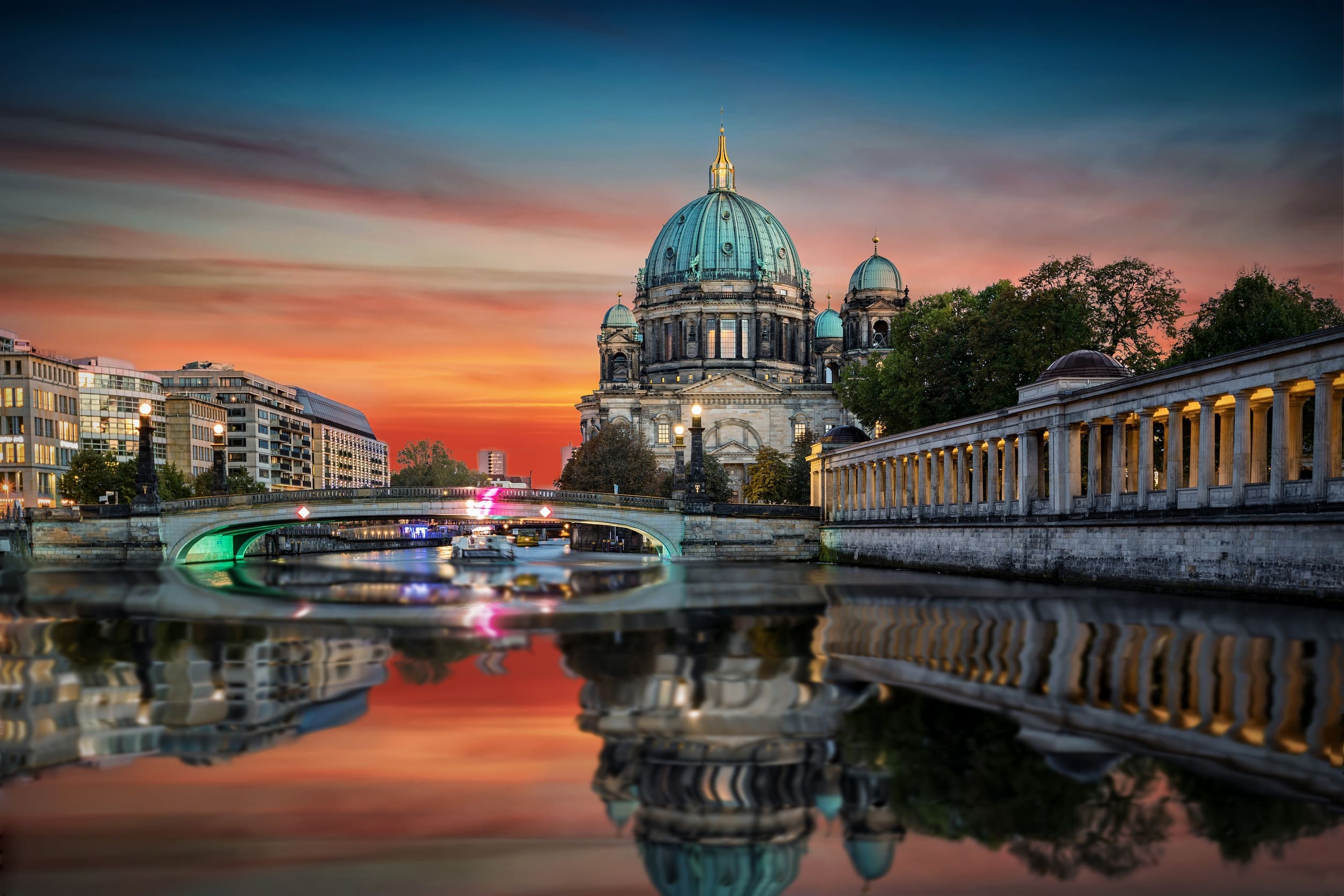一張令人印象深刻的黃昏或黎明照片，展示了德國柏林大教堂 (Berliner Dom) 和施普雷河 (Spree River)。