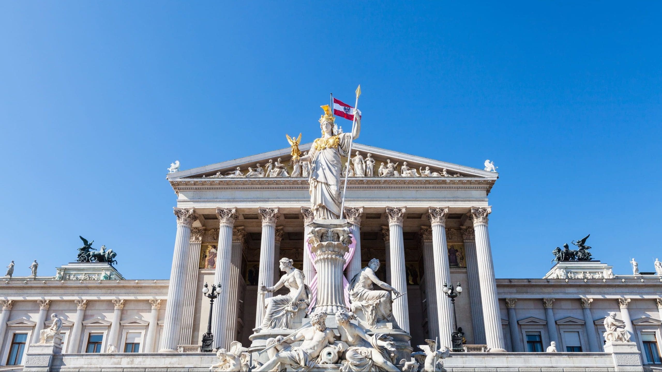 低角度拍攝的德國奧地利國會大廈 (Austrian Parliament Building) 宏偉的新古典主義立面及其著名的帕拉斯·雅典娜噴泉 (Pallas Athene Fountain)。